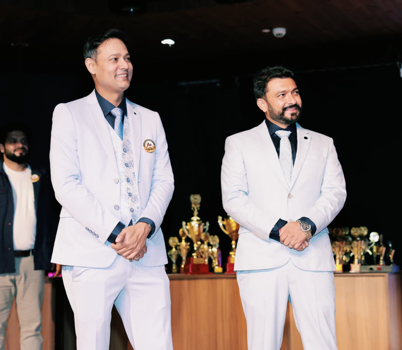 Two hosts in white suits on stage